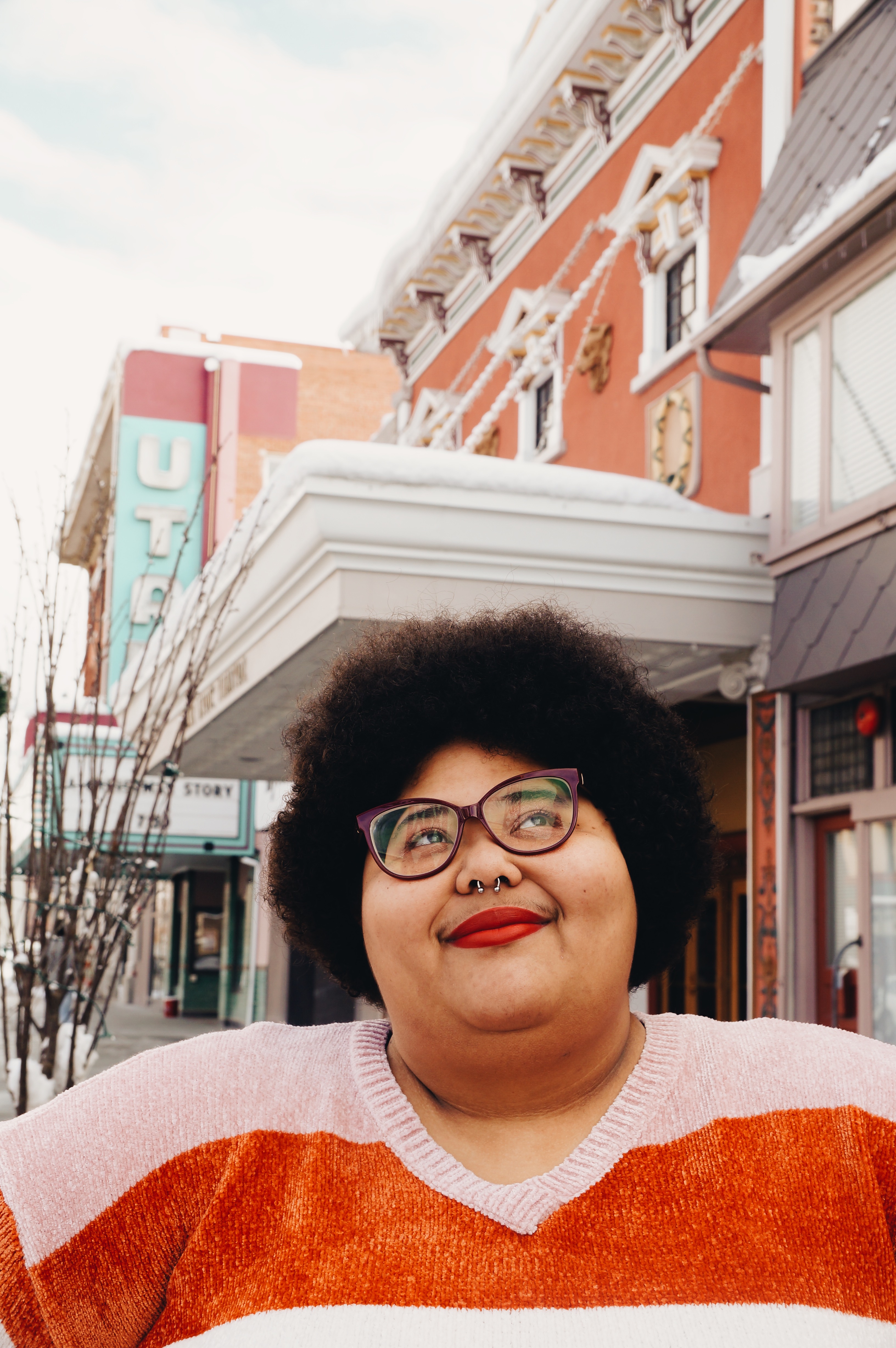 Headshot of slam poet TaneshaNicole standing in front of colorful buildings